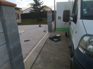 Installation de portail ou clôture : camion blanc garé près de piliers en parpaings, outils Bosch sur sol gravillonné et bétonné.